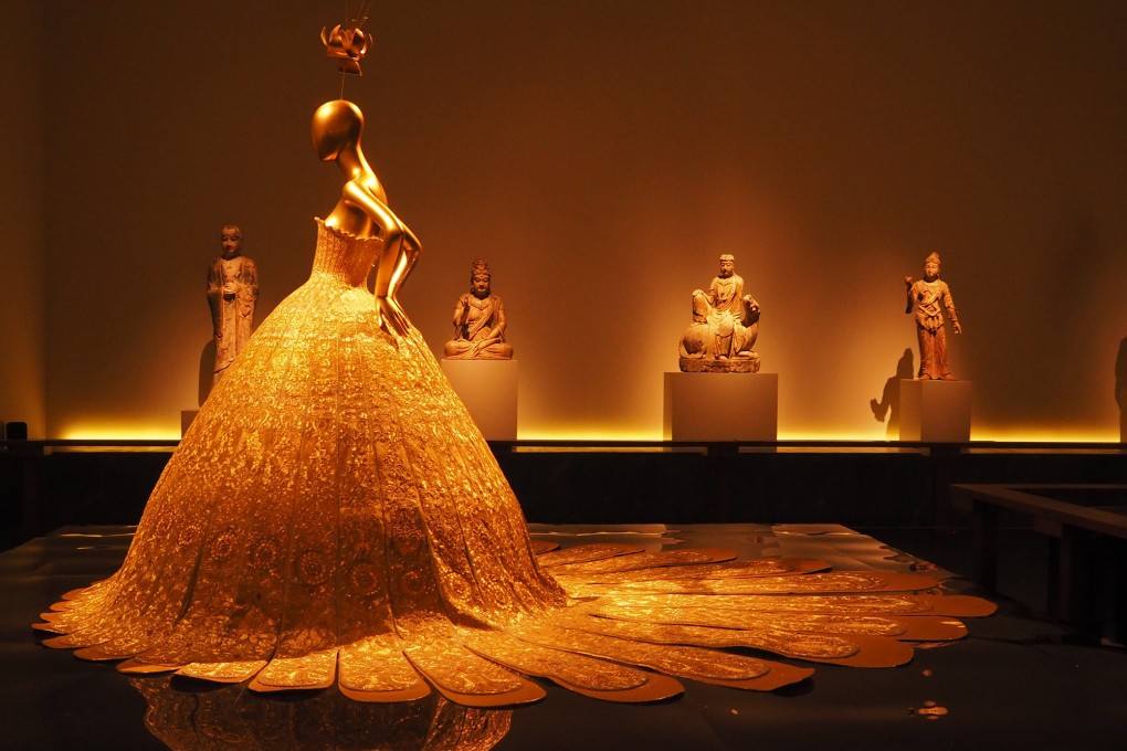 A modern-day Guo Pei gold gown featuring a traditional Western profile is juxtaposed with ancient Buddhist sculptures at the Metropolitan Museum's exhibition, "China: Through the Looking Glass". Photo: The Washington Post/Vern Yip