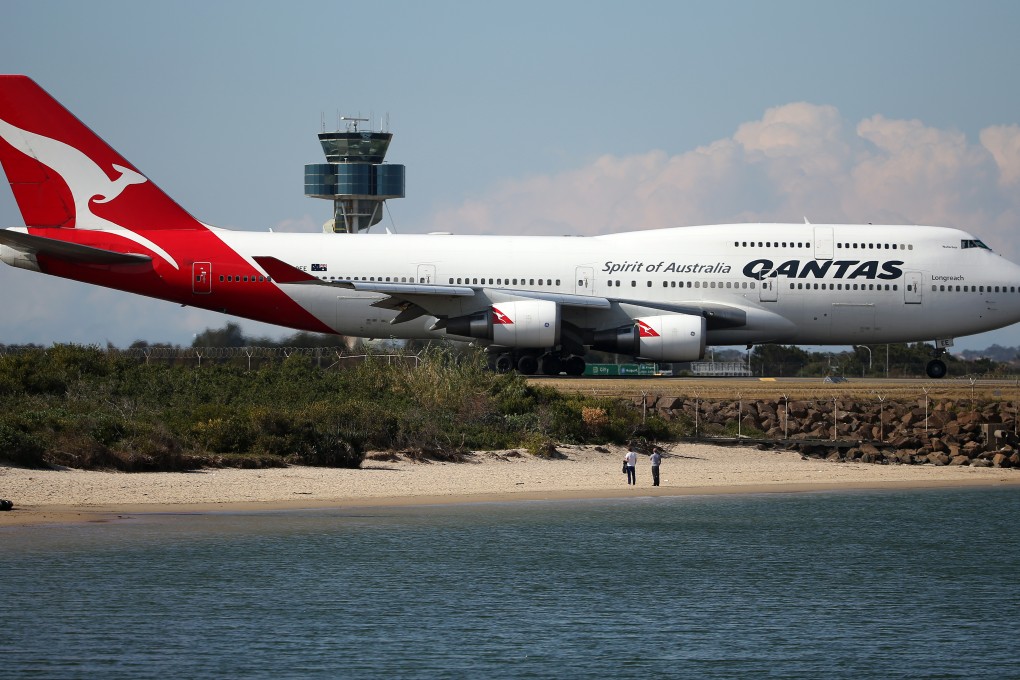 Two people watch from a beach as a Qantas plane taxies on the runway at Sydney Airport as the airline said it will expand its fleet after a quick turnaround. Photo: AP