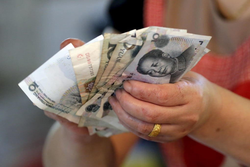A vendor holds Chinese yuan notes as the International Monetary Fund deferred to 2016 the possible inclusion of the currency in the Fund's SDR basket. Photo: Reuters