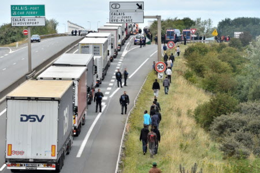 Police stand on the road to prevent migrants from climbing aboard trucks travelling to Britain on ferries or the nearby Channel Tunnel shuttle train in Calais. Photo: AFP