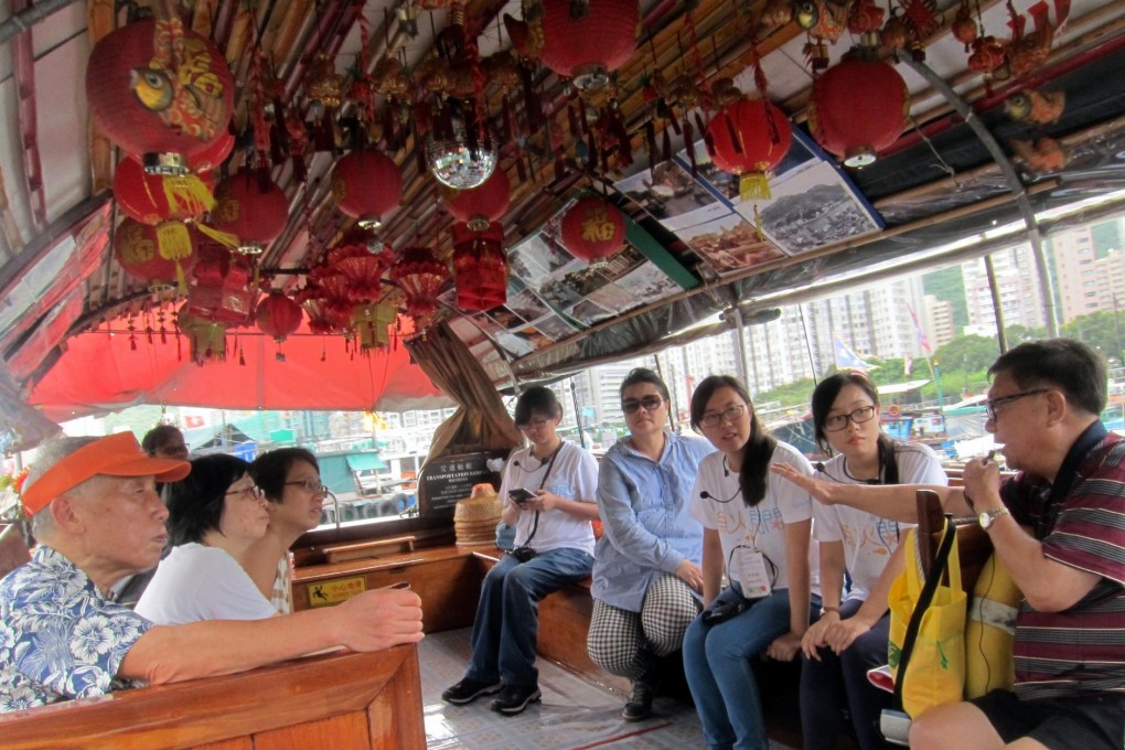 Former fisherman Leung Pak-sun (far right) welcomes a group to his boat during a tour of Aberdeen Harbour.