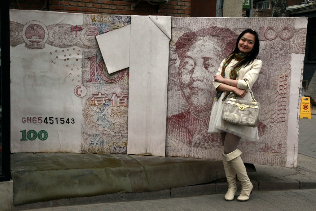 A Chinese woman poses for photos near a sculpture depicting a yuan note at an art district in Beijing. Photo: AP