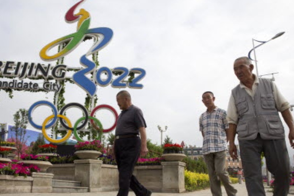 People walk past the Olympic bid logo in Chongli county, Hebei, where Nordic skiing and ski jumping events will be held. Photo: AP