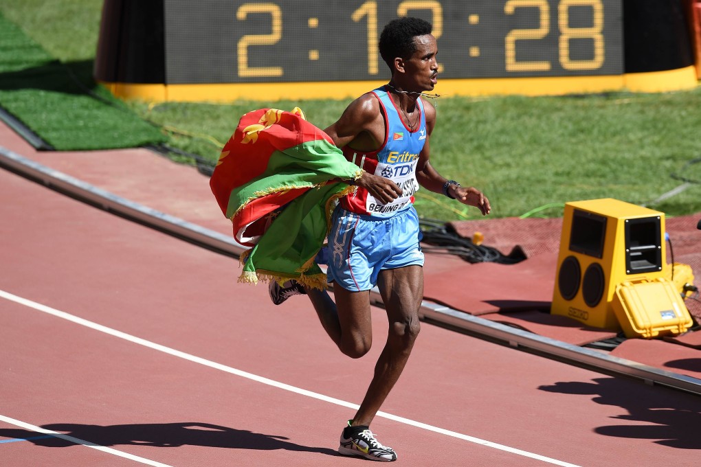 Wrapped in the Eritrean flag, Ghirmay Ghebreslassie races to victory in the men's marathon at the "Bird's Nest" National Stadium in Beijing. Photo: AFP