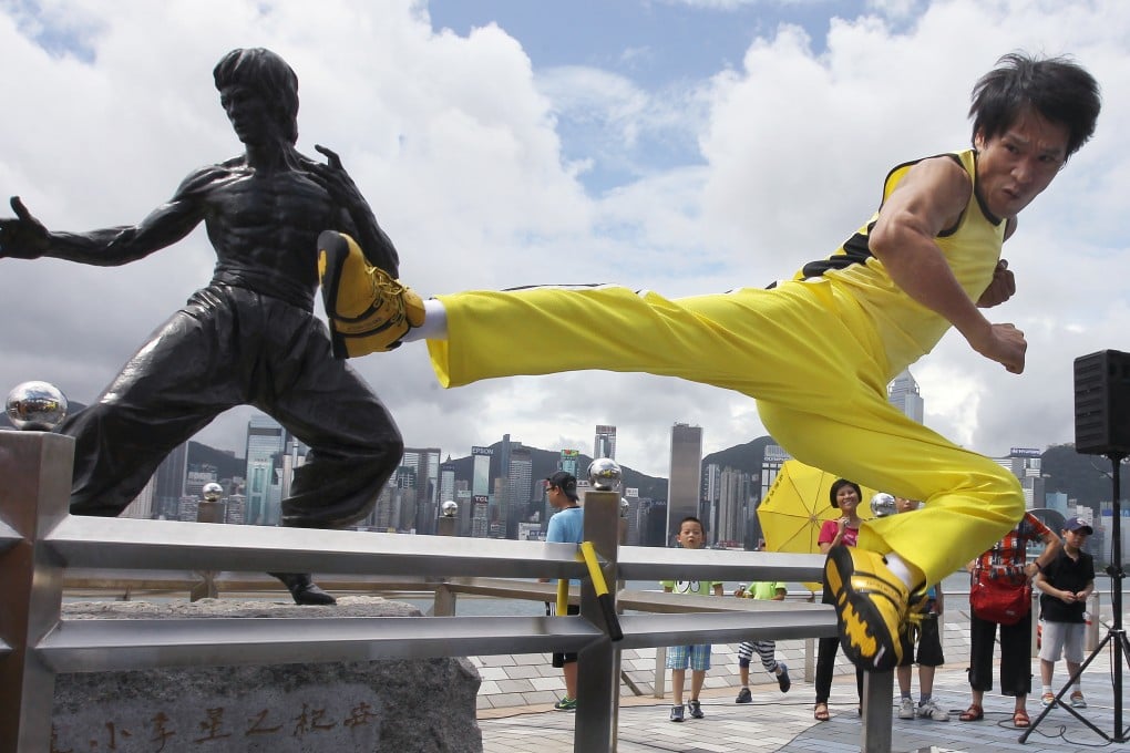 Tourists look on as a Chinese actor mirrors the fighting skills of film icon Bruce Lee at the Avenue of Stars, which offers great views of the Hong Kong skyline. Photo: Samantha SinPhoto: Edward Wong