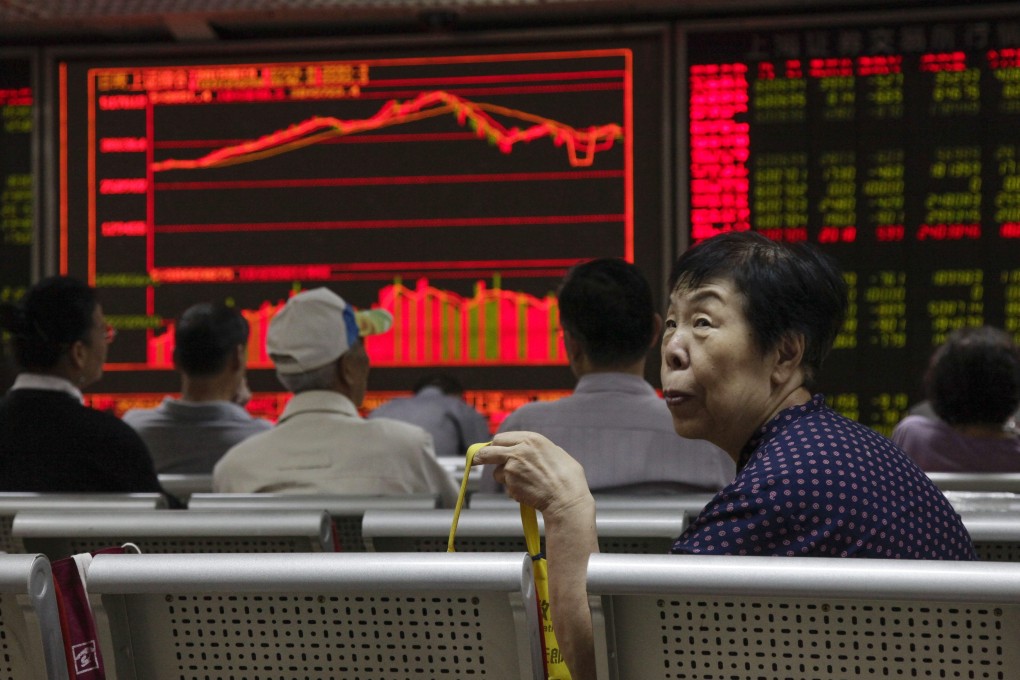 An investor looks up from her seat as stock data is displayed on an electronic board at a securities brokerage house in Beijing, China. Photo: EPA