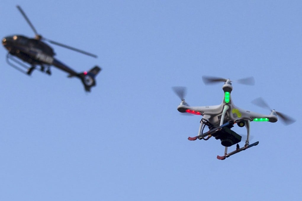 A police helicopter flies past a drone Quadcopter in west Baltimore, Maryland. Photo: Reuters