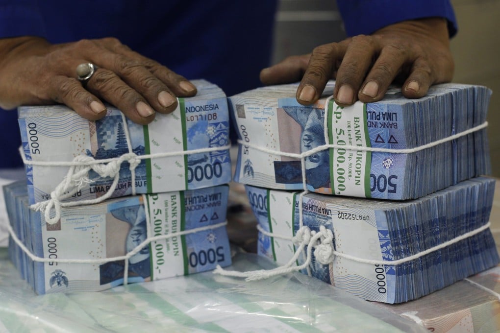 A worker prepares bundles of rupiah bank notes in Jakarta as sharp falls in emerging market currencies will also likely lead to further declines in emerging market equities. Photo: Reuters