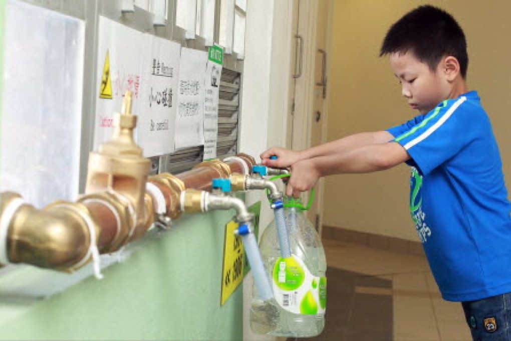 Edmond Ng Yat-long, eight, fetch water from newly installed temporary pipes at Sheung Ching House in Kai Ching Estate on August 17. Photo: May Tse