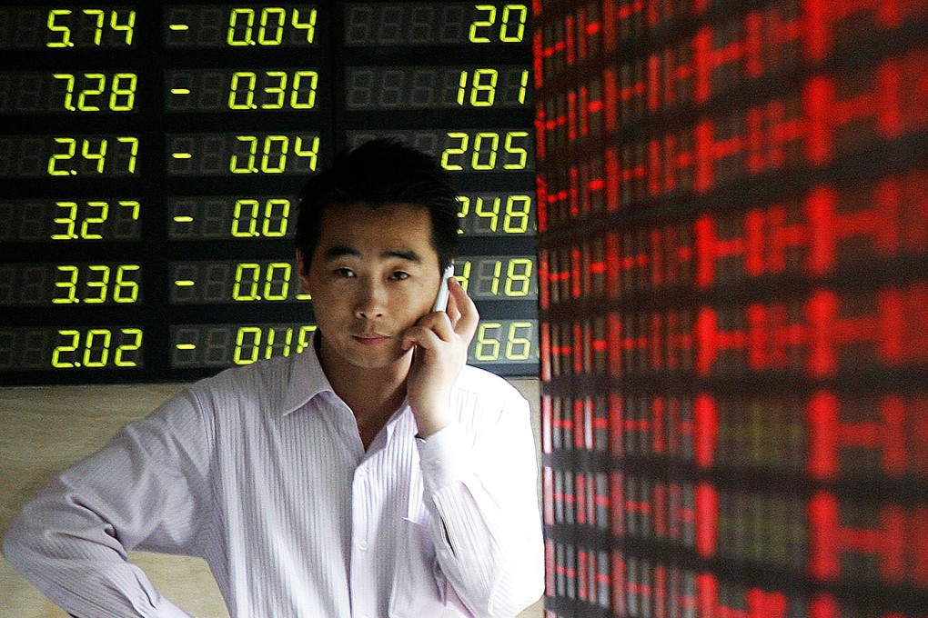 An investor talks on his mobile phone in front of a stock price monitor at a private securities company in Shanghai. Photo: AP