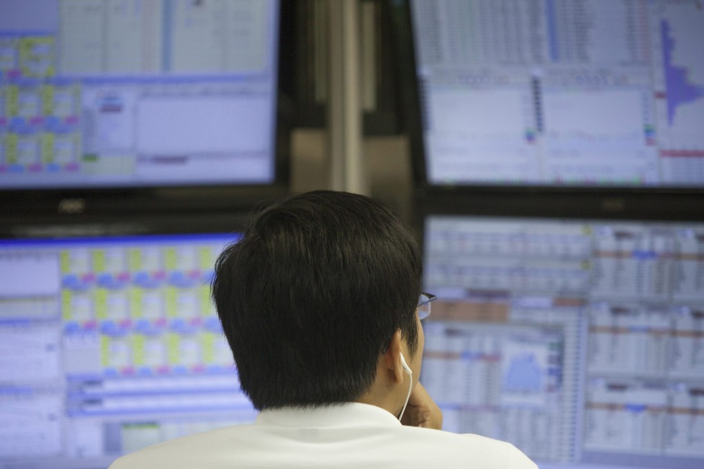 A stock broker looks at screens at a brokerage at the Hang Seng Index in Hong Kong as a study shows appear to be passive managers for their customers. Photo: EPA