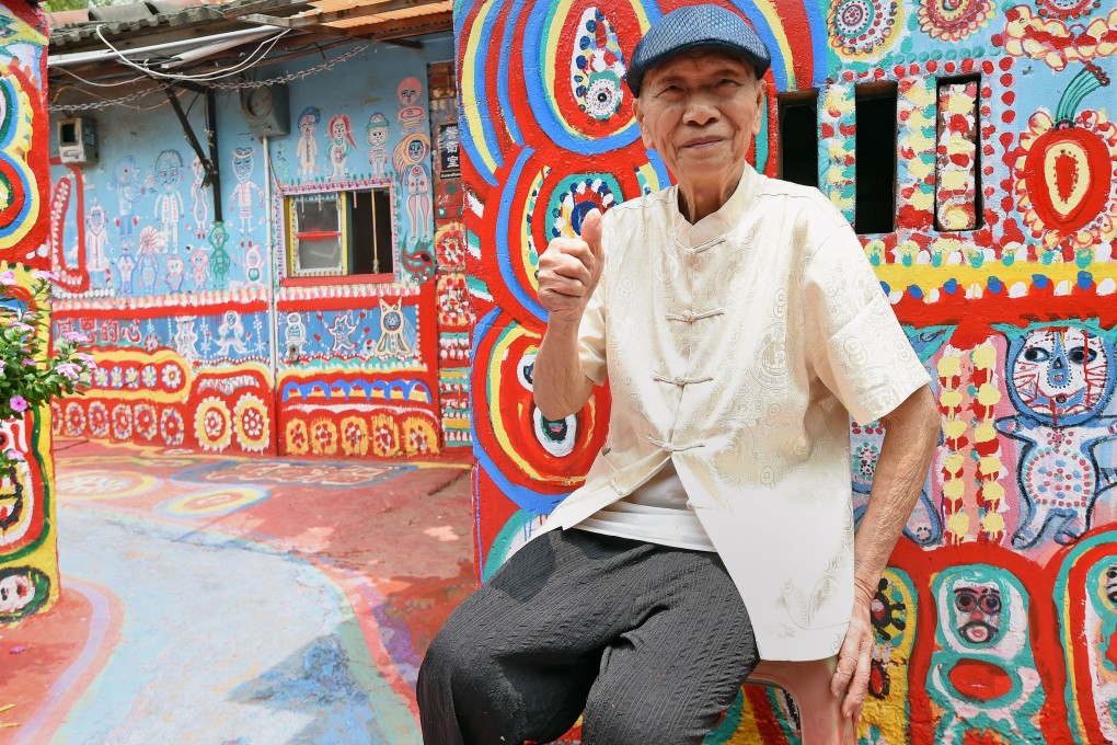 Huang Yung-fu posing for a photo next to his artwork in the Rainbow Village. Photo: AFP