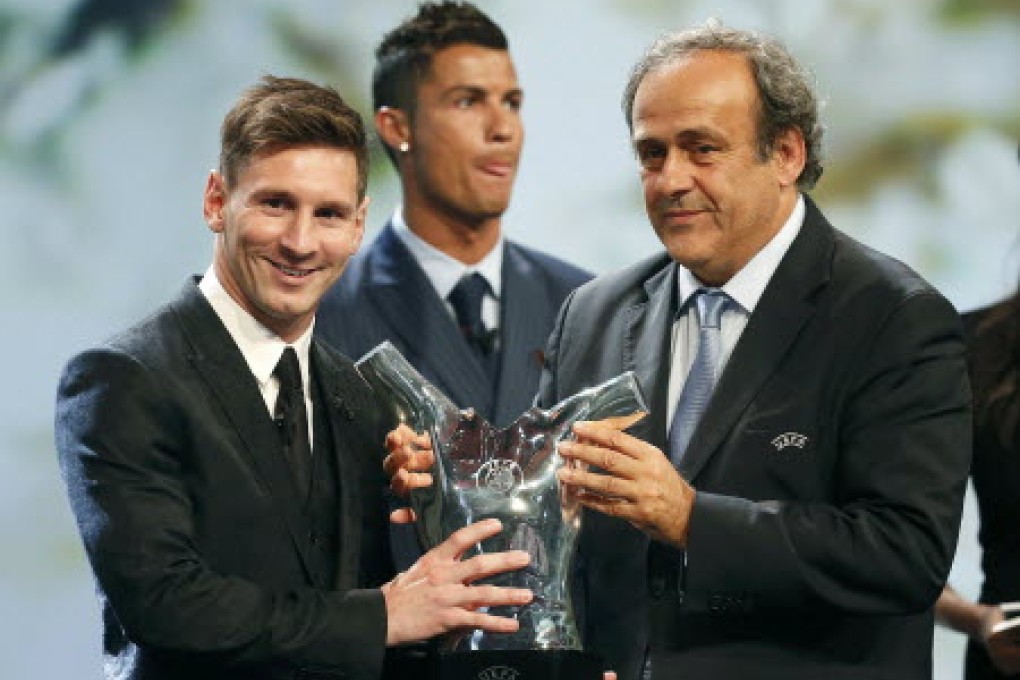 Barcelona's Lionel Messi receives his award from Uefa  president Michel Platini for the best player in Europe as Cristiano Ronaldo looks on at Monaco's Grimaldi Forum. Photo: Reuters