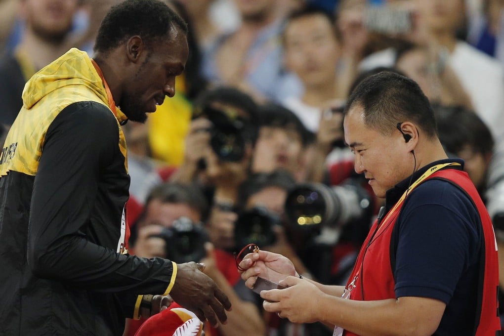 CCTV journalist Song Tao presents Jamaica's gold medallist Usain Bolt with a gift during the victory ceremony for the men's 200m. Photo: AFP