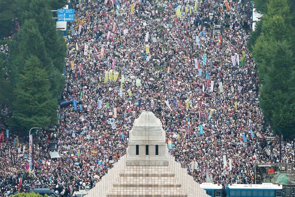 People hold placards and shout slogans as they gather to protest against Japan's Prime Minister Shinzo Abe's security bill outside the parliament in Tokyo. Photo: Kyodo/Reuters