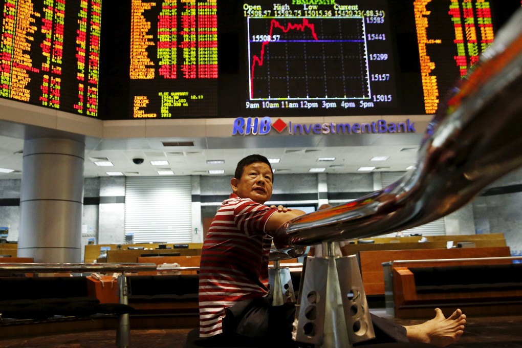 A man peers at prices on Malaysia's stock market as Credit Suisse analysts say Southeast Asian equities should be shunned given the yuan devaluation and the prospect of an interest rate rise in the US. Photo: Reuters