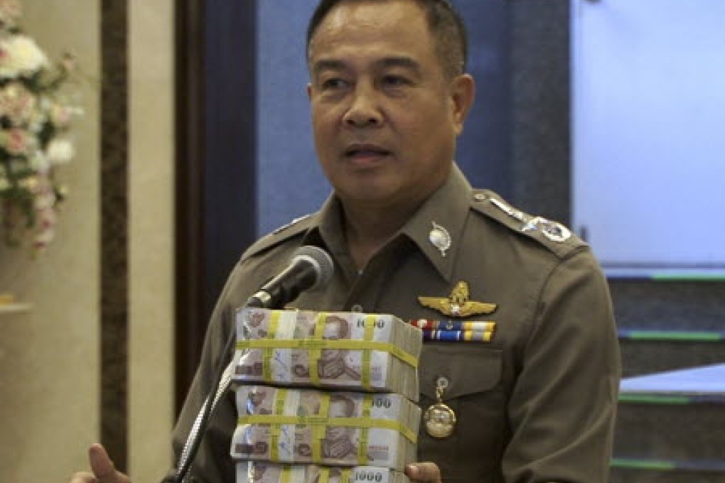 National police chief Somyot Poompanmoung holds a cash reward at a press conference in Bangkok. Photo: AP