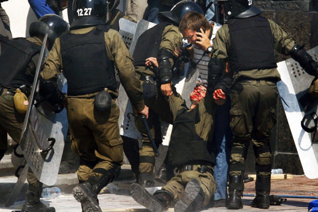 Police help a wounded colleague during clashes with activists from radical Ukrainian parties in front of the Kiev parliament. Photo: AFP