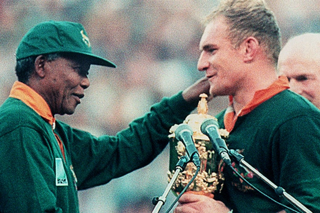 President Nelson Mandela presents the Rugby World Cup to South African compatriot Francois Pienaar in 1995 while wearing a Springboks jersey which became a symbol of national reconciliation. Photo: AFP