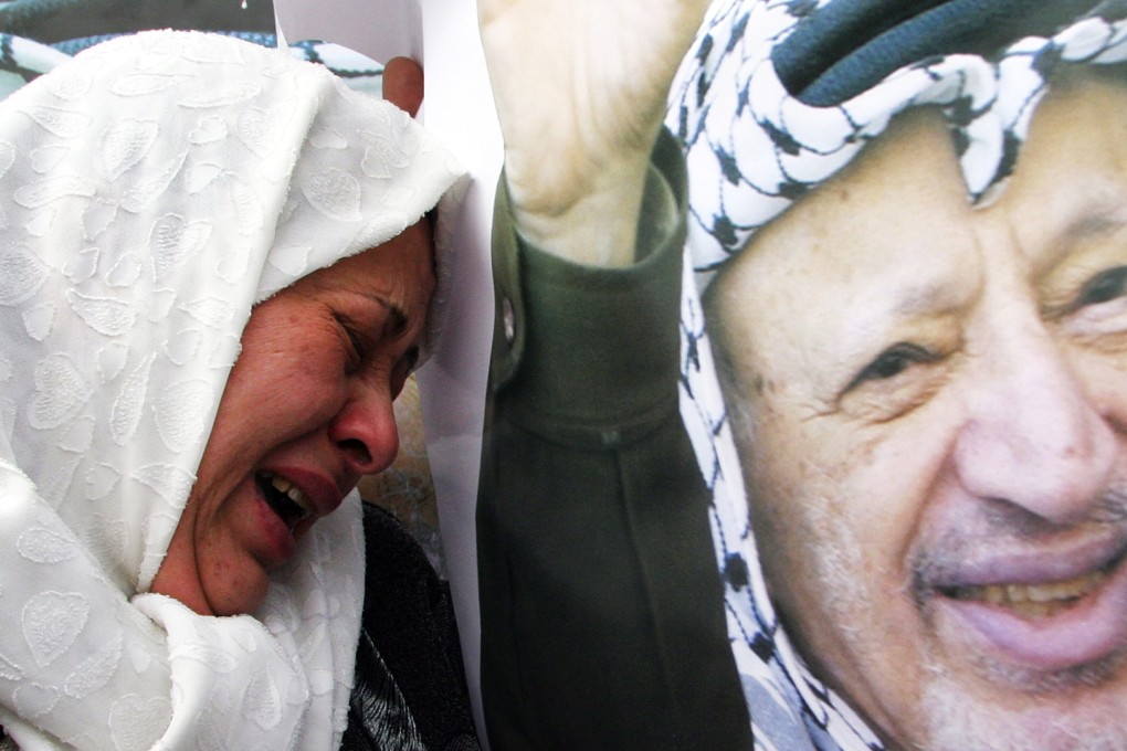 A Palestinian woman cries next to a portrait of Palestinian leader Yasser Arafat outside the Muqataa, Arafat's West Bank headquarters, in Ramallah in 2004. Photo: AFP