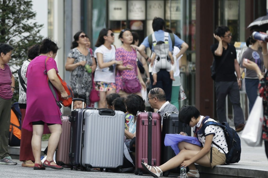A group of Chinese tourists sit with their suitcases in the Ginza district of Tokyo, Japan, in August. Photo: Bloomberg