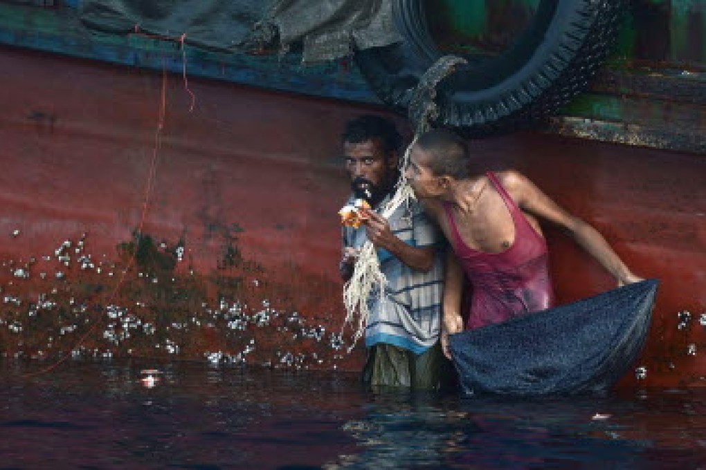 Two rescued migrant men standing next to a boat in Bayuen, Indonesia's East Aceh province. File photo: AFP