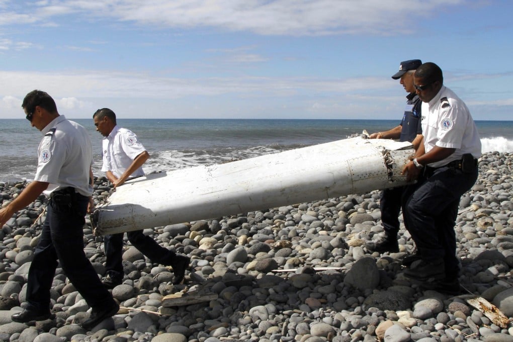 Officers carrying a flaperon  from an aircraft apparently washed ashore in Saint-Andre de la Reunion in July. Photo: EPA