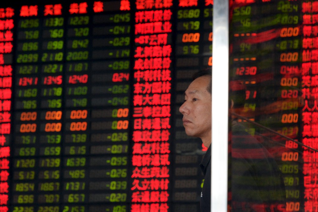 An investor stands in front of an electronic board showing stock information at a brokerage house in Shanghai on Wednesday. Photo: Reuters