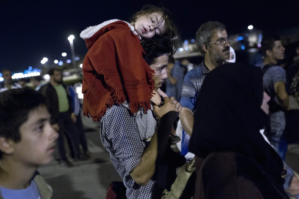 A migrant family waits to board a bus after disembarking from a ferry at the port of Piraeus in Athens this week. Photo: AFP