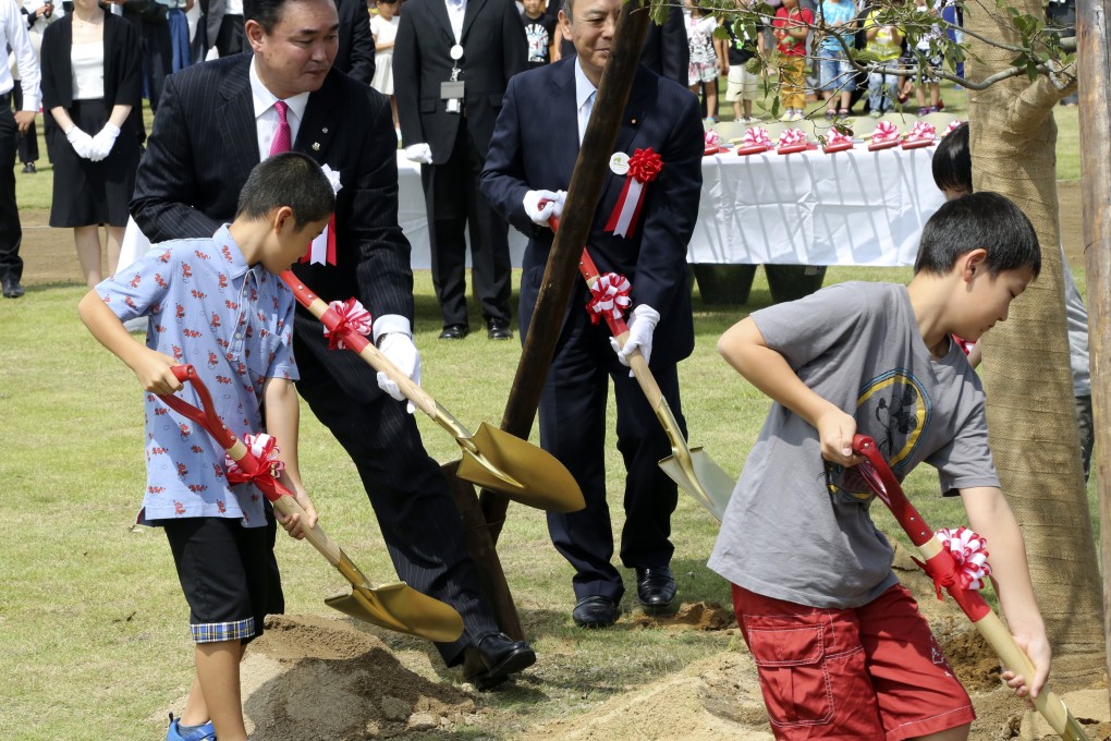 Noraha Mayor Yukiei Matsumoto, rear left, plants a tree with children of the town's residents in northern Japan on Saturday. Photo: AP