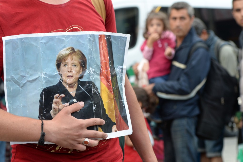 A refugee holds a picture of German Chancellor Angela Merkel after the arrival of refugees at the main train station in Munich. Photo: AFP