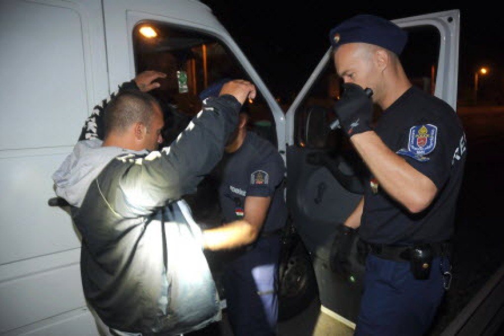 Police officers inspect a van containing several migrants after the arrest of a suspected smuggler in Hungary. Photo: AFP
