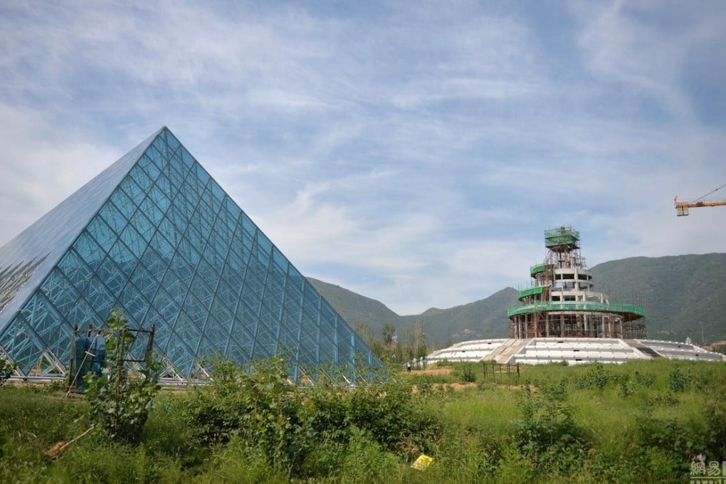 The replica Louvre Pyramid sits in the overgrown field of an amusement park/movie set in Shijiazhuang, Hebei province. A replica of Beijing's Temple of Heaven is under construction in the background. Photos: Netease.com