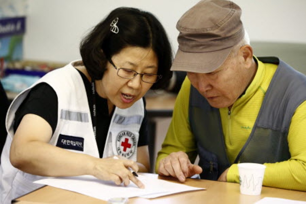 South Korean Choi Sang-Bae, 74, (right), who was separated from his family during the Korean War, is helped by a member of the Red Cross to fill a request to reunite with family members. Photo: EPA