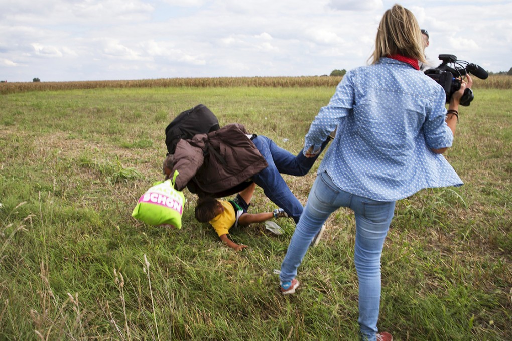 The camerawoman from N1TV sticks out her leg, sending a refugee and his young child sprawling. Photo: Reuters