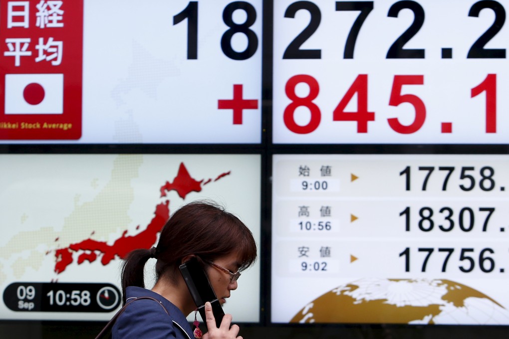 A pedestrian on his cell phone walks past an electronic board showing the Nikkei Index in Japan as it posted its strongest single-day rally in 7 years. Photo: Reuters