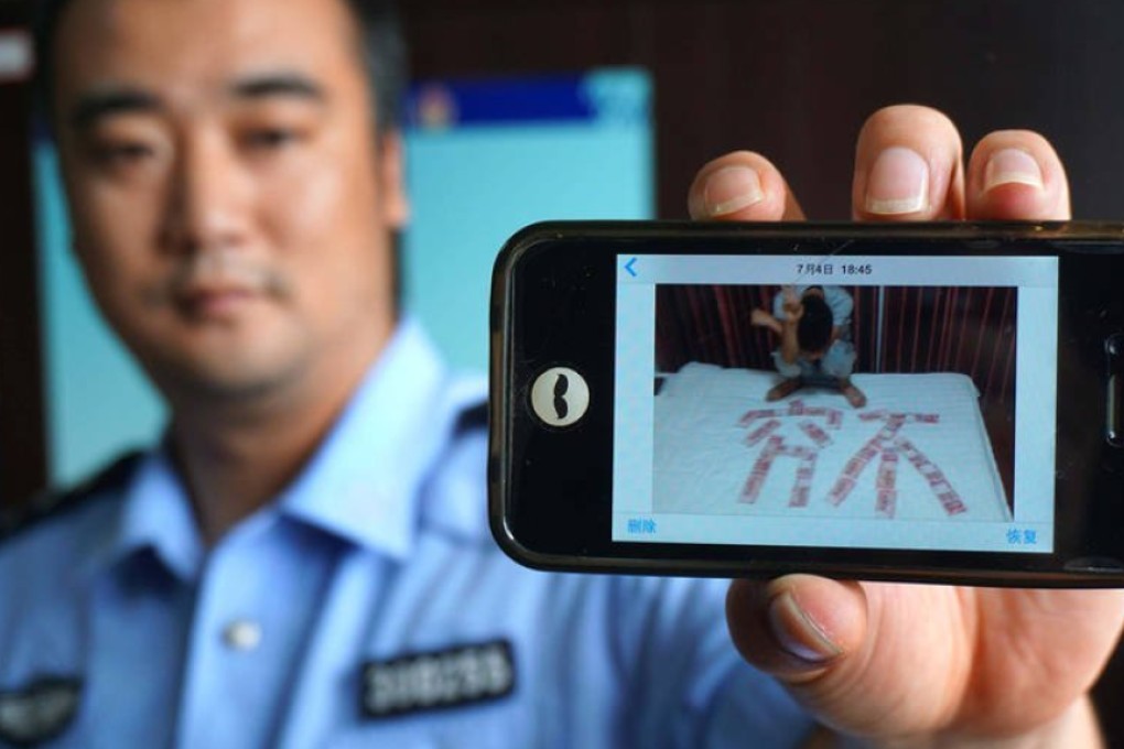 A Chinese policeman shows the mobile phone of one of the two suspects displaying a photo of one of them with money that is believed to have been stolen. Photo: Qq.com