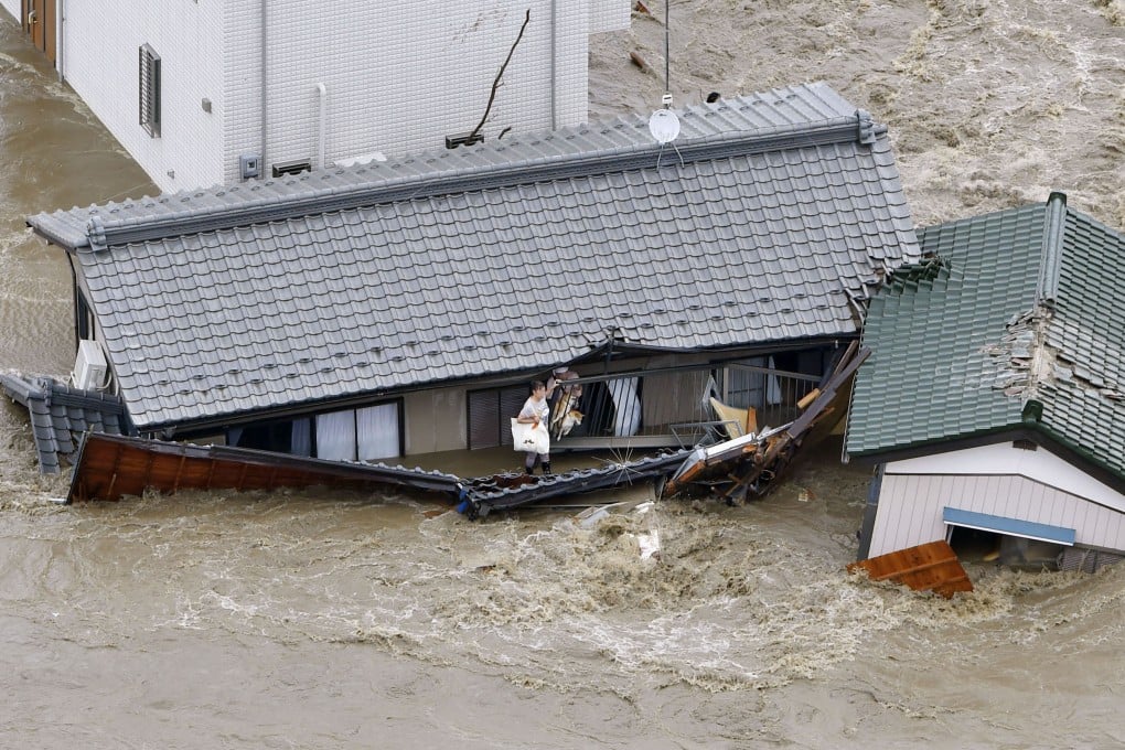 A woman awaits rescuers inside a house being washed away. Photo: Reuters