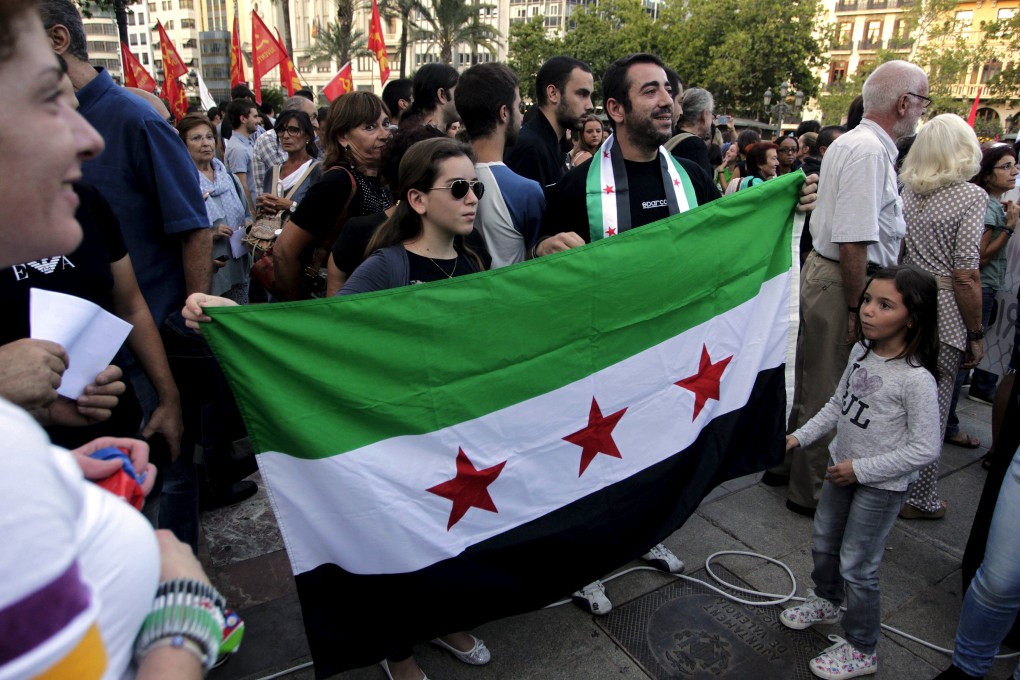 A man holds a Syrian flag next to his children as protestors gather in Spain in solidarity with refugees reaching Europe from the war torn country. Photo: Reuters