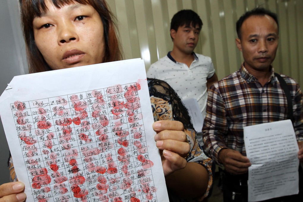 Factory workers Qin Renfang (left) and Wang Qiang with a list of names of the workers at the mainland plant. Photo: Franke Tsang