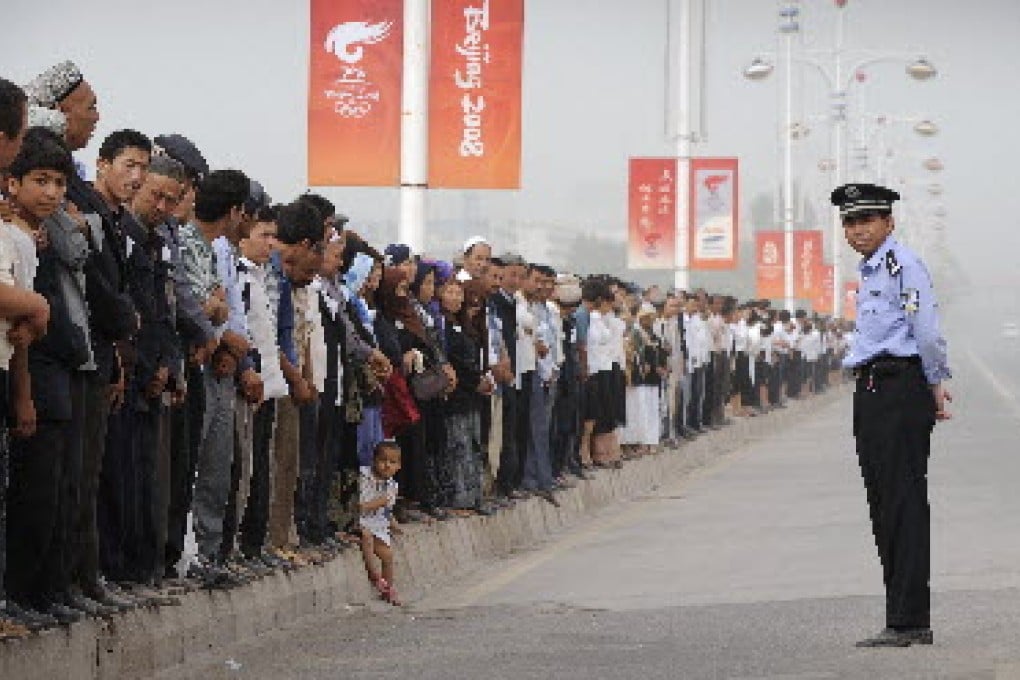 A Chinese policeman watches as ethnic Uyghurs line the street for a ceremony in 2008 to remember 16 Chinese police officers killed in an alleged terrorist attack in Xinjiang's famed Silk Road city of Kashgar in China's Xinjiang region. Photo: AFP
