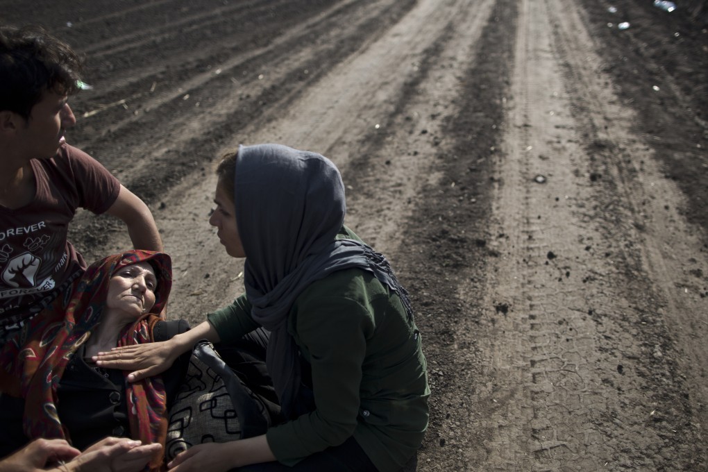 An Afghan refugee is helped by her son, daughter and a volunteering doctor after collapsing while crossing the border between Serbia and Hungary. Photo: AP