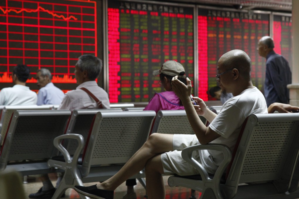 An investor uses a mobile phone while monitoring stock market data at a securities brokerage house in Beijing. Photo: EPA