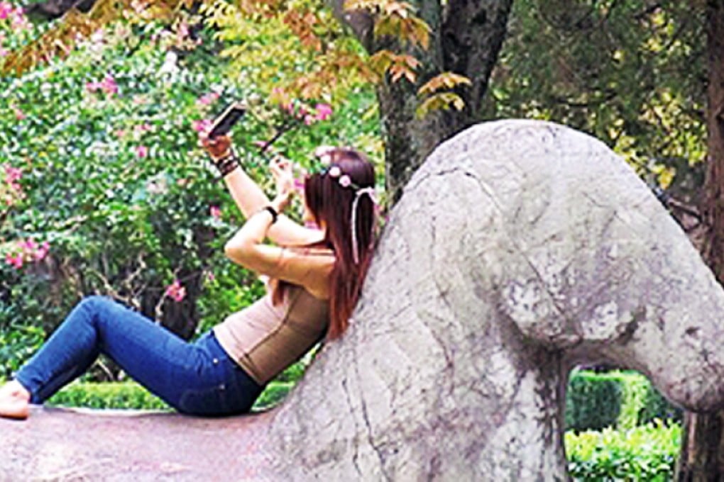 A Chinese woman spent about five minutes sitting on the Ming dynasty statute in Nanjing while posing for photographs. Photo: SCMP Pictures