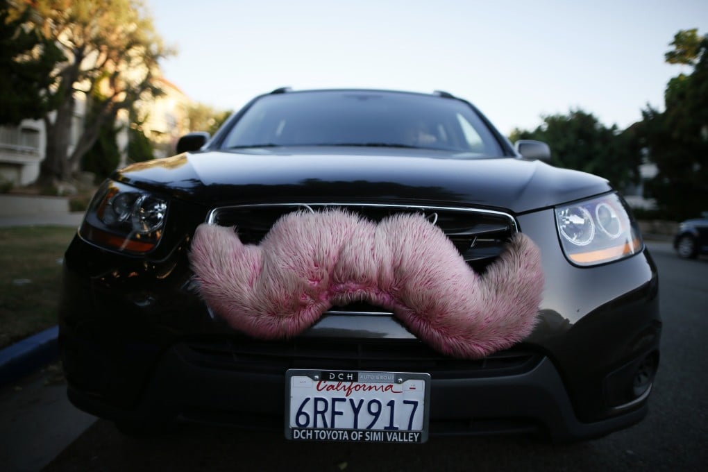 A driver with the US ride-sharing service Lyft waits for a customer on a street in Santa Monica, California. Lyft’s pink mustache was the first branding the company used until 2015, when it switched to a smaller, glowing magenta mustache that sits on a driver's dashboard. Photo: Reuters