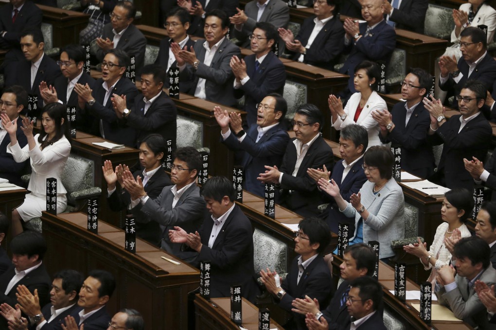 Japan's ruling party lawmakers, who supported the legislation loosening post-war constraints on use of force by the military, applaud after the new laws are passed in a vote by Tokyo's upper house.Photo: AP