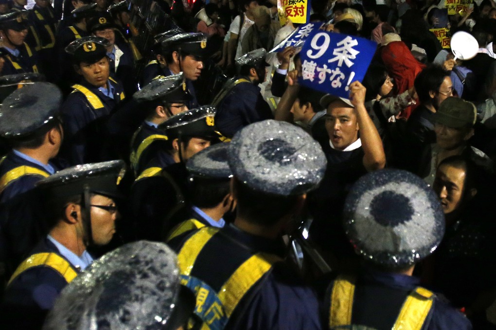 A protester shouts slogans as he is surrounded by police officers during a rally against the Japanese government in front of the parliament building in Tokyo on Friday. Photo: AP