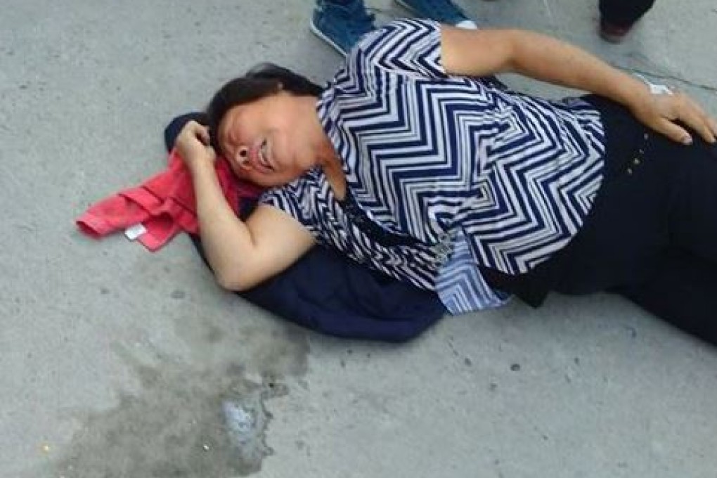 A woman lies on the ground waiting to be taken to hospital. Photo: ChinaFotoPress