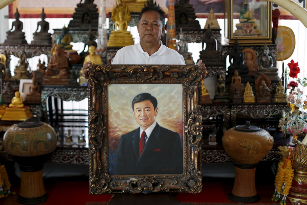 Red shirt movement leader Kwanchai Praipana poses with a photo of former PM Thaksin Shinawatra at his office in Udon Thani, Thailand. Photo: Reuters