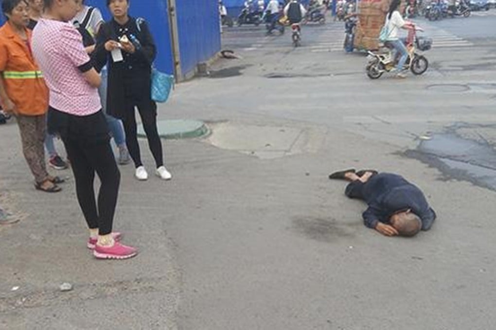 By-standers crowd around the elderly man collapsed on the street in Zhengzhou, Henan province. Photos: SCMP Pictures